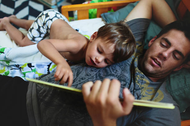 Papa qui lit une histoire à son fils avant de le mettre au lit